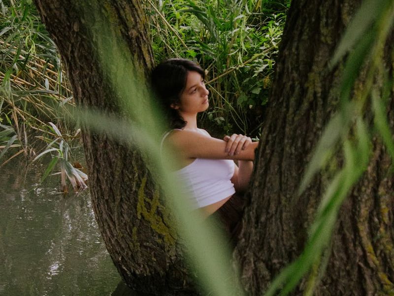 Person meditatively looking at a distant green forest scene